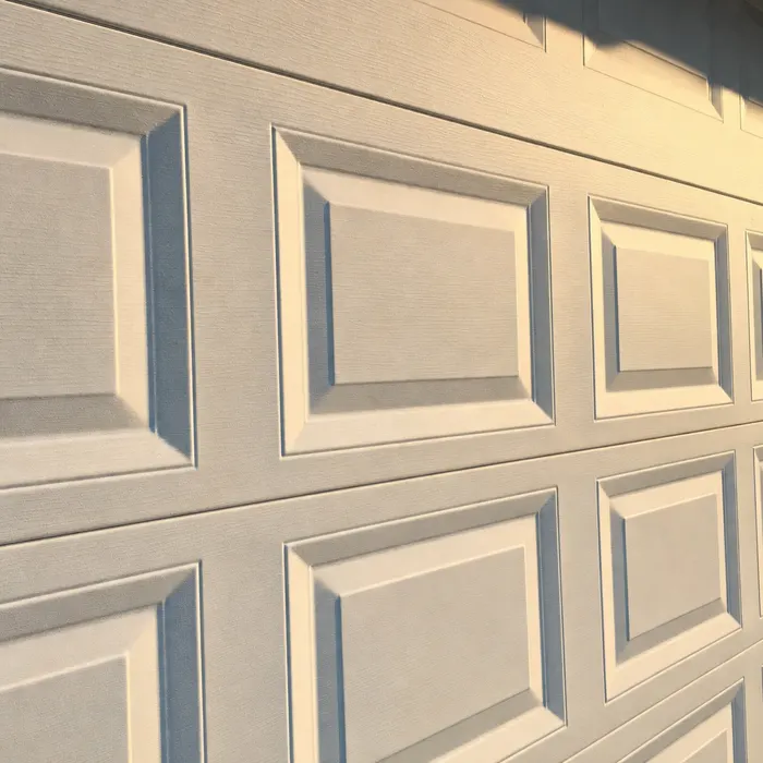 Raised-panel steel garage door sections in raking golden light